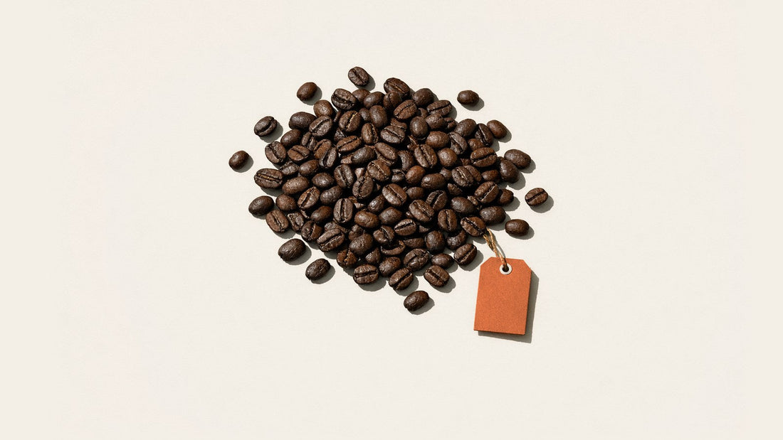 Loose roasted coffee beans with a blank orange tag on white paper